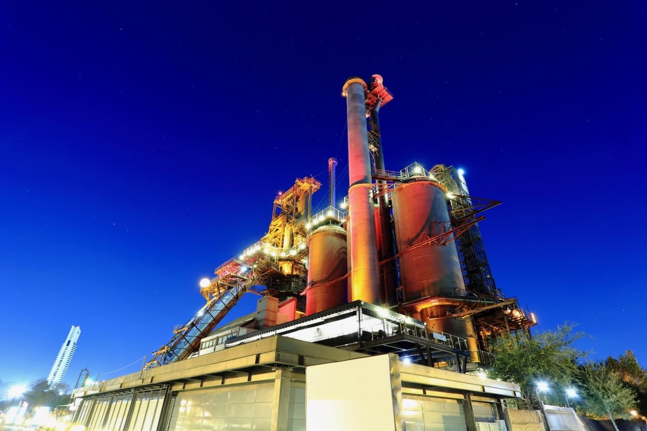 Vista nocturna de una planta industrial iluminada, símbolo del funcionamiento continuo que requieren Equipos de Aire Acondicionado Industriales de alta capacidad.