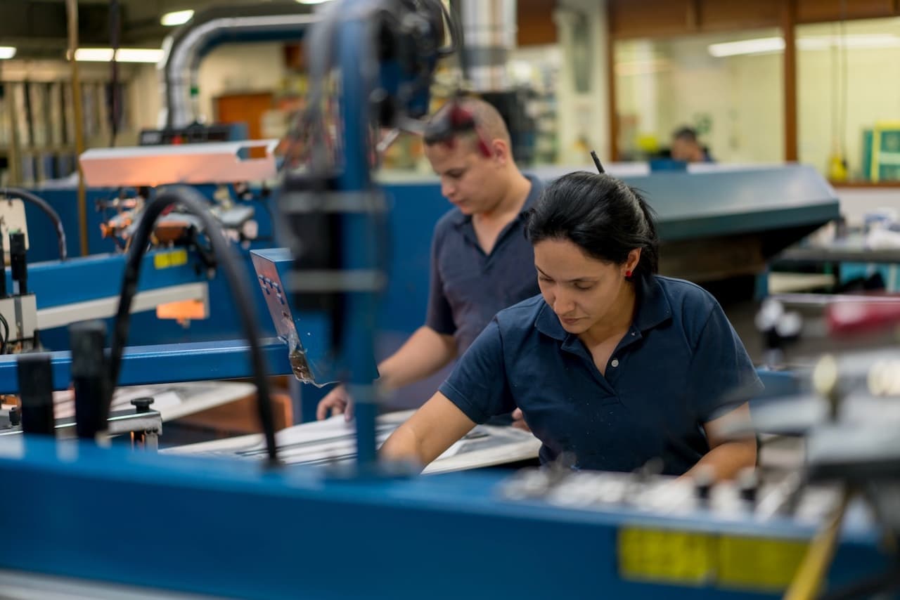 Trabajadores operando maquinaria en una fábrica ventilada por CW-H15, asegurando una buena calidad de aire en el lugar de trabajo.