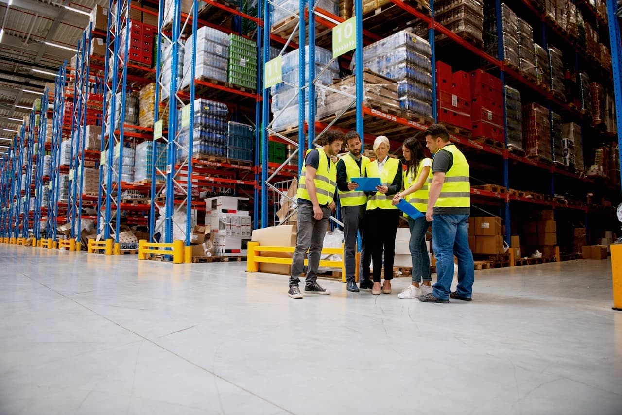 Grupo de trabajadores con cascos y chalecos de seguridad en un almacén industrial, representando la gestión de proyectos HVAC CW-3.