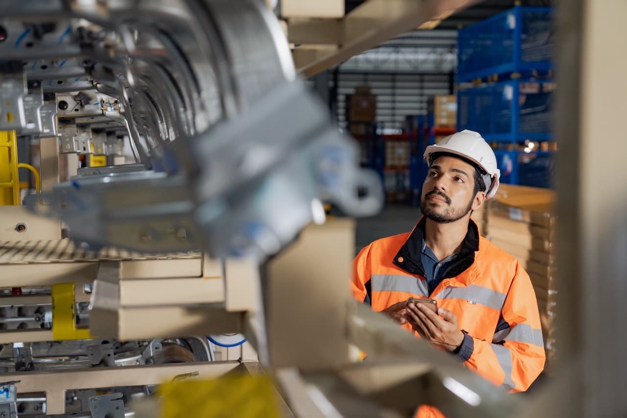 Técnico ajustando componentes de una unidad HVAC en una línea de producción, asegurando la calidad en los Equipos de Aire Acondicionado Industriales.