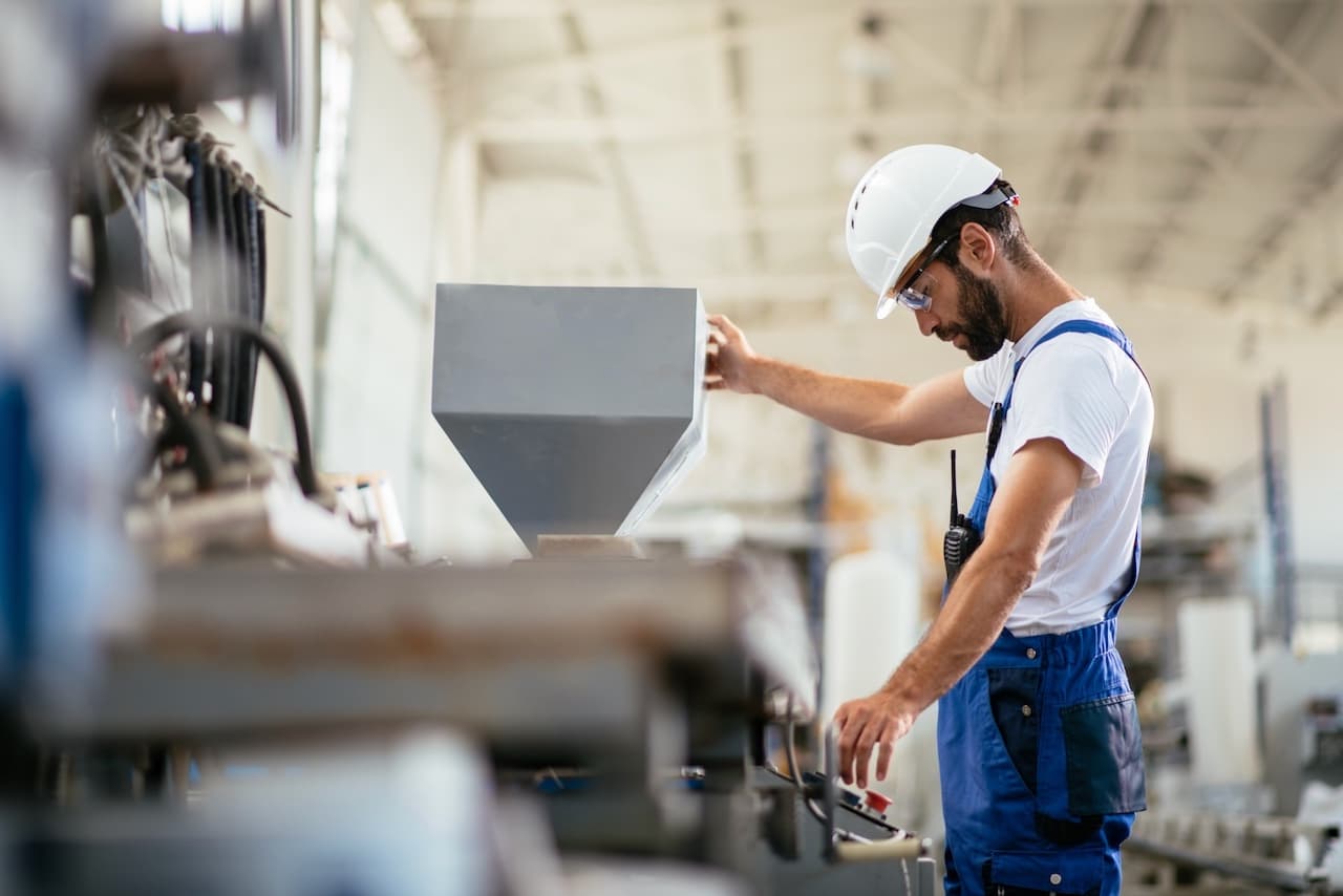 Empleado manipulando un equipo en una línea de producción, mientras Mobile Max 2 asegura un ambiente fresco y ventilado en la fábrica.