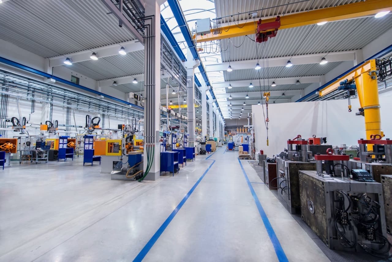 Vista interior de una fábrica moderna con líneas de producción automatizadas, usando Equipos de Aire Acondicionado Portátiles para controlar el clima del espacio.