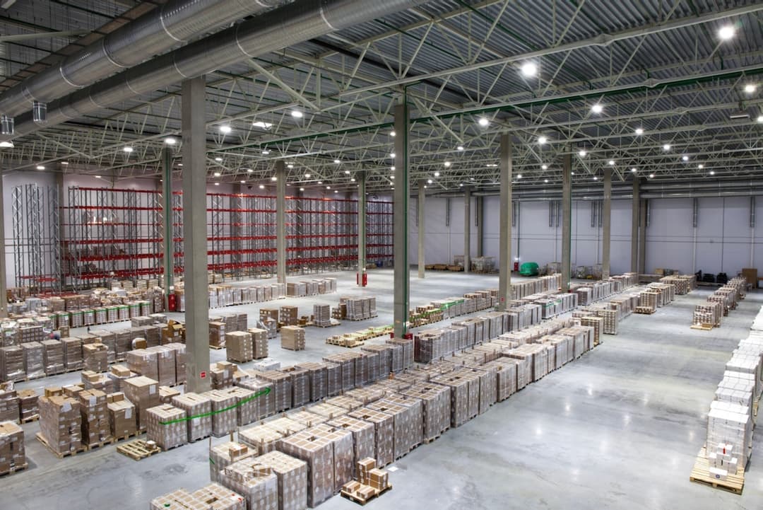 Interior de una planta industrial con líneas de producción y cajas apiladas, donde se utiliza Equipos de Aire Acondicionado Portátiles para mantener el ambiente controlado.