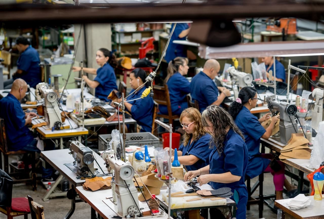 Trabajadores en una línea de ensamblaje manual en un entorno ventilado con Equipos de Aire Acondicionado Portátiles, asegurando un ambiente laboral cómodo.