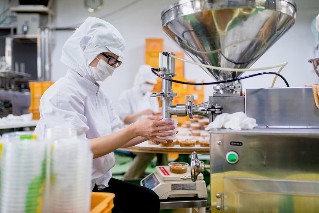 Trabajadores en una línea de producción usando trajes protectores, operando maquinaria bajo ventilación proporcionada por Equipos de Aire Acondicionado Portátiles.