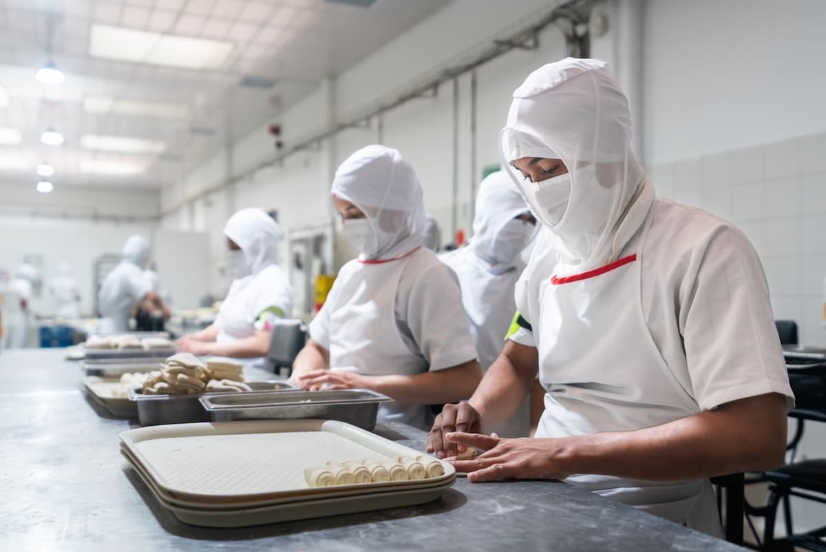 Trabajadores en una línea de producción de alimentos, con Equipos de Aire Acondicionado Portátiles para mantener estándares de calidad y seguridad.