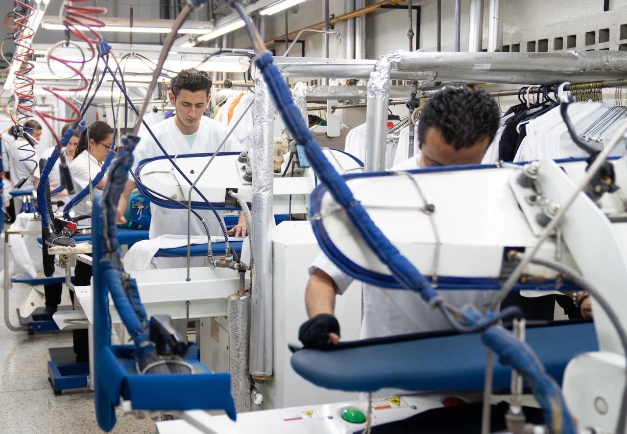 Trabajadores revisando las conexiones de un sistema CW80 IEC en una línea de producción, asegurando un ambiente de trabajo seguro.