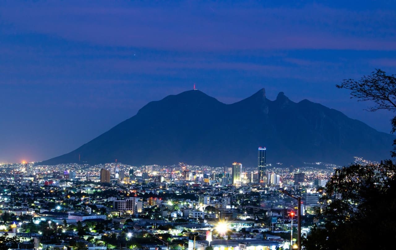 Vista de Monterrey al atardecer con la Sierra Madre al fondo, reflejando la necesidad de climatización adecuada con Equipos de Aire Acondicionado Industriales.