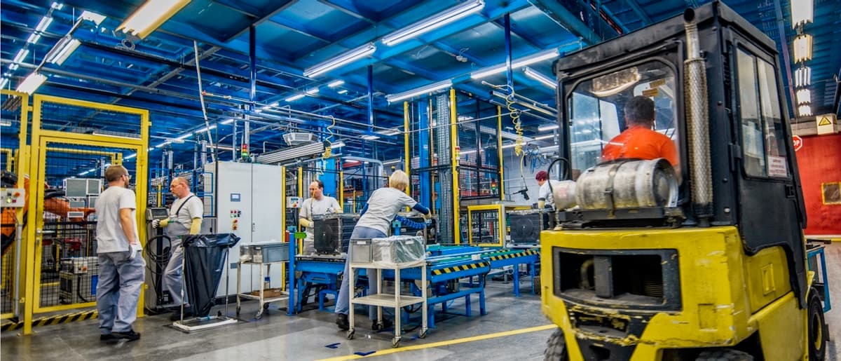 Fábrica moderna con maquinaria y operarios en acción, mostrando la eficacia del Mobile Max 2 en mejorar las condiciones laborales.