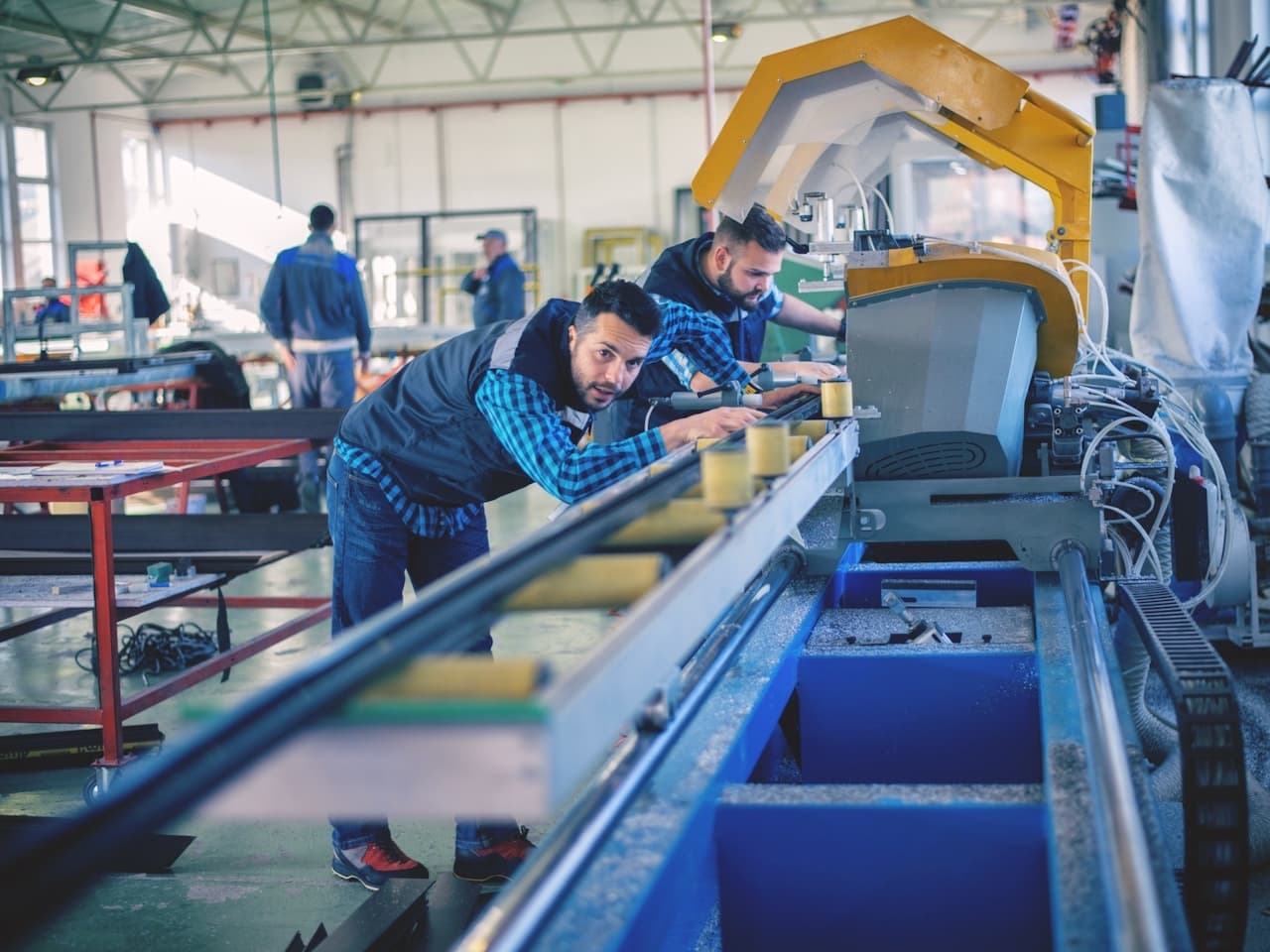 Técnico ajustando una máquina en un taller industrial, con Mobile Max 2 proporcionando ventilación adecuada para mantener el equipo y personal frescos.