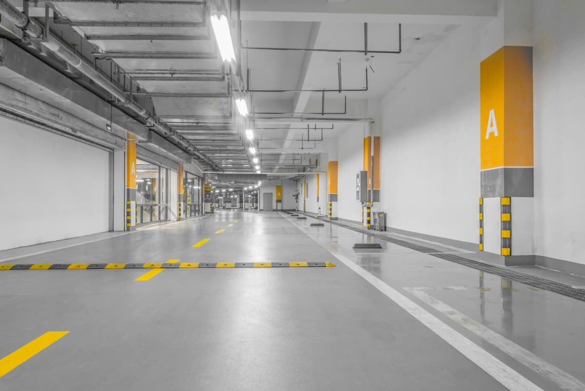 Pasillo amplio y bien iluminado de una planta industrial, equipado con ventiladores TBSI-580 para mantener el aire en movimiento.