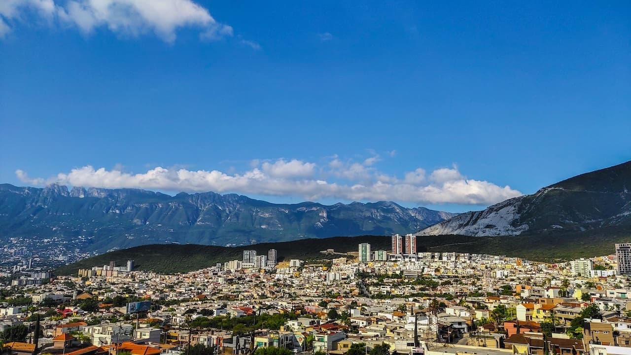 Paisaje urbano de Monterrey con vista a las montañas y edificios residenciales, resaltando el uso de ventilación para confort ambiental.